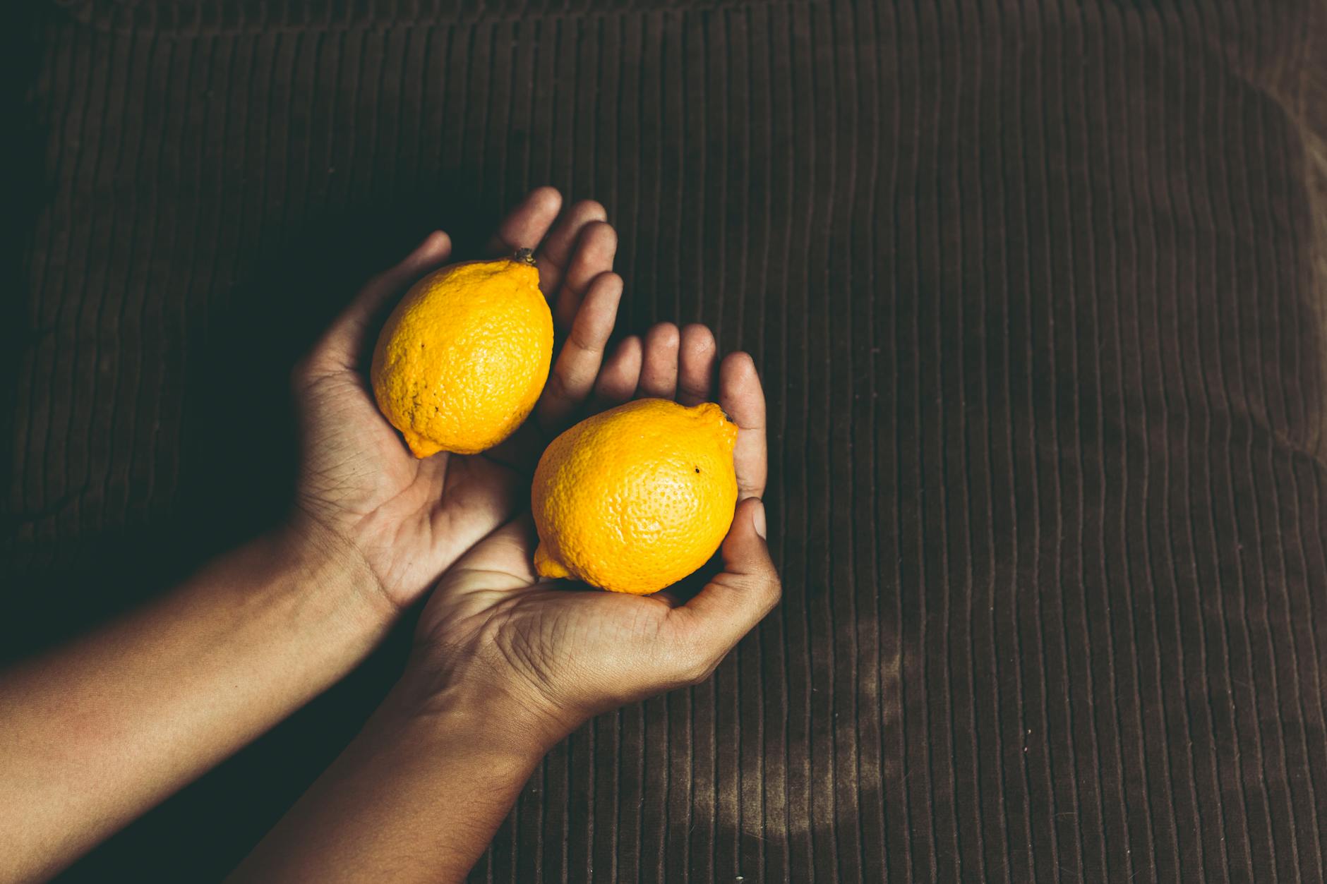 Hand holding fresh lemons, representing the gentle, intentional approach to gradual pleasure