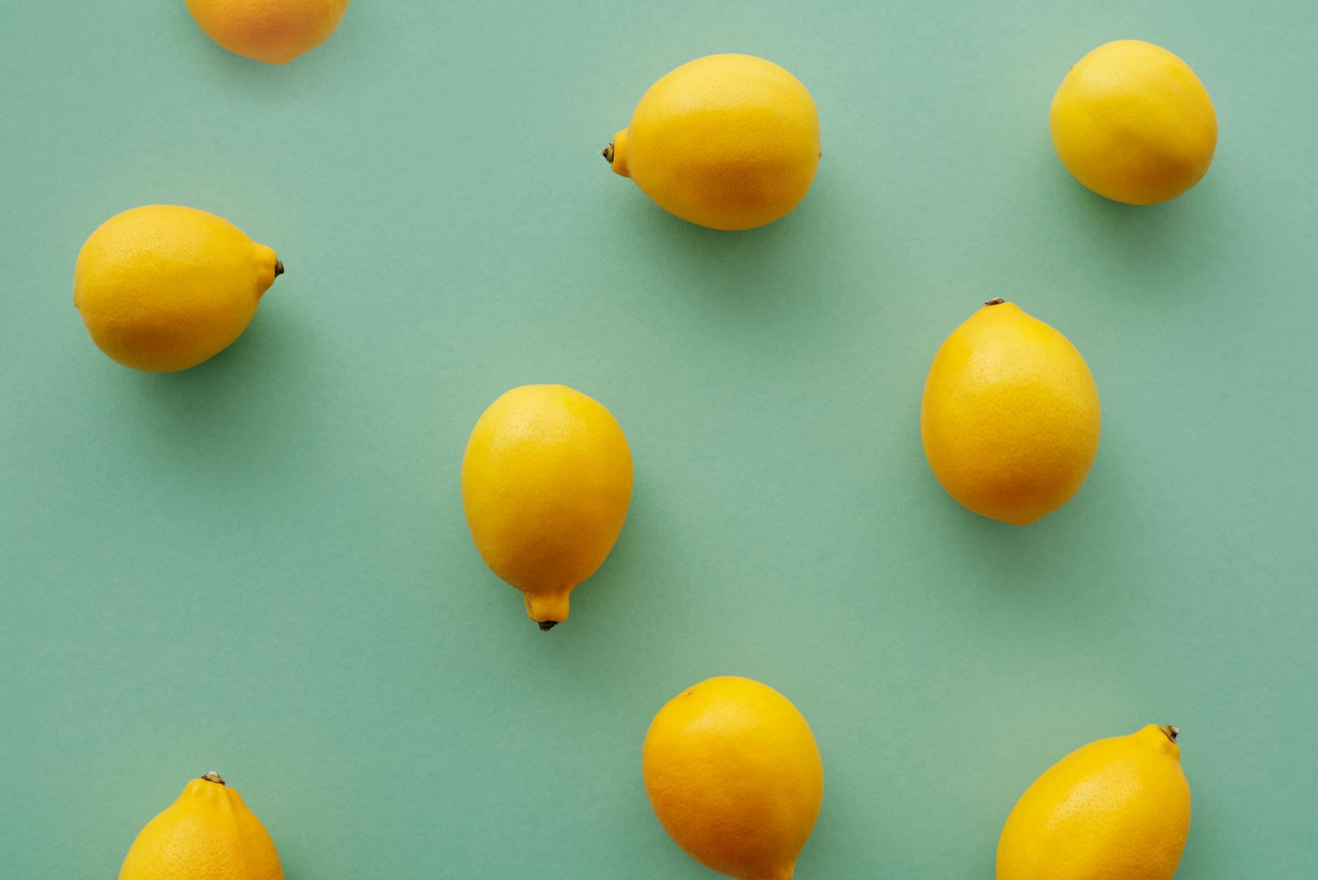 Fresh bright yellow lemons arranged on a pastel green background, symbolizing renewal and fresh intimacy
