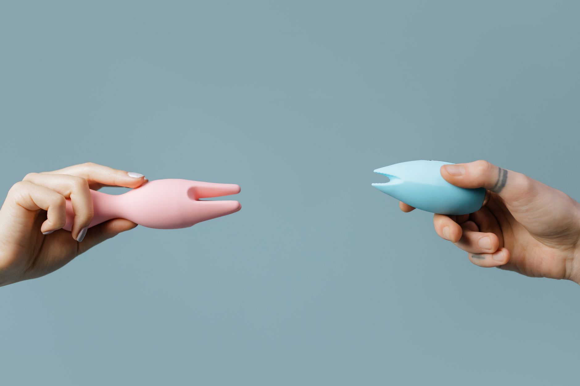 Two hands holding vibrators against a pastel background, symbolizing pleasure recovery