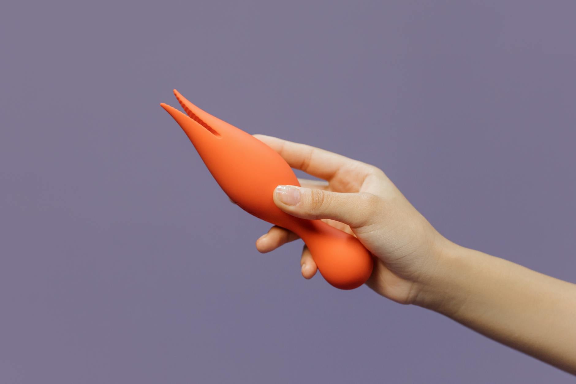 Close-up of a hand holding a lemon vibrator against a purple backdrop, showcasing sensual design and texture