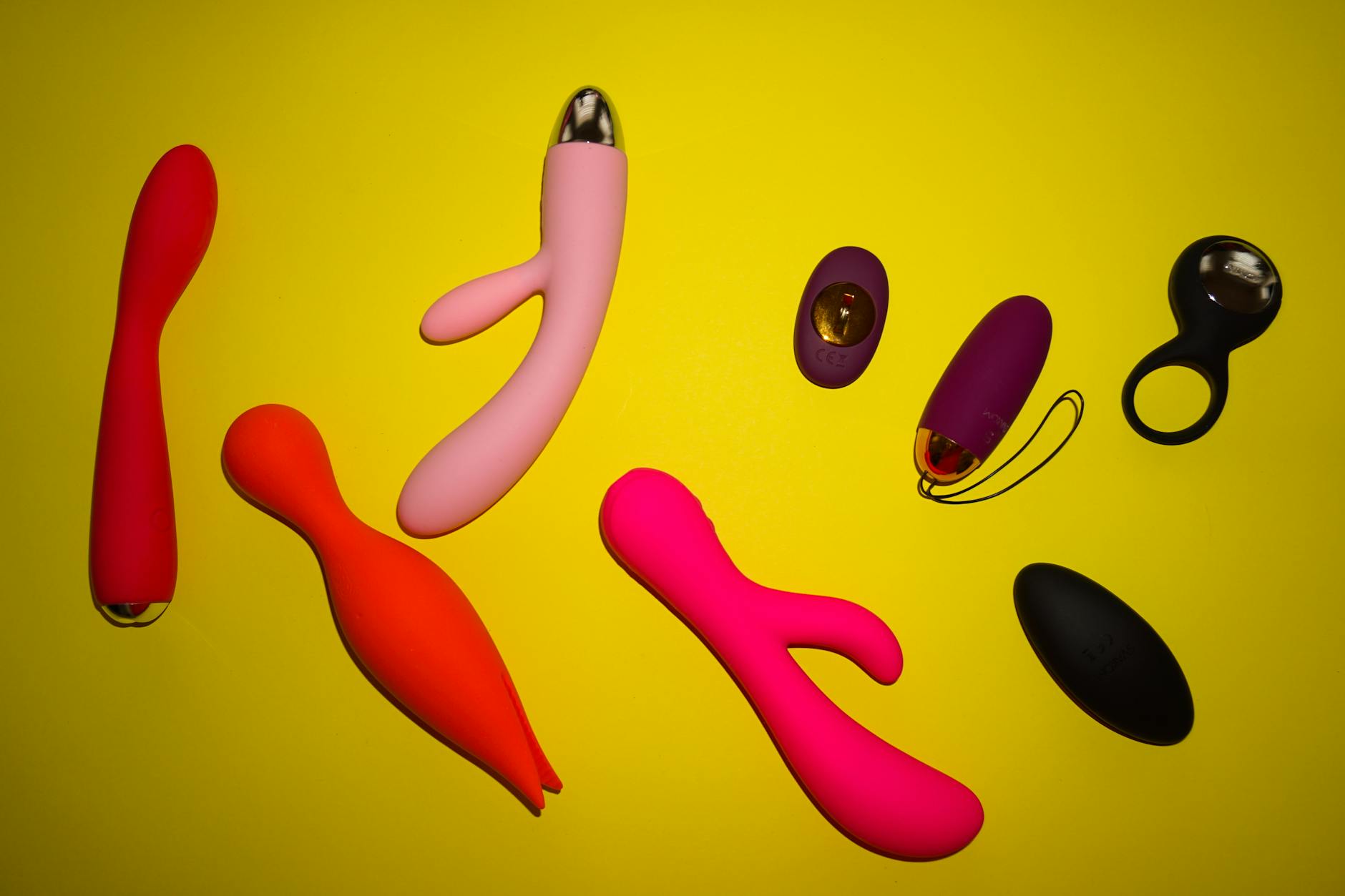 A blue clitoral vibrator surrounded by flowers on a bright yellow background