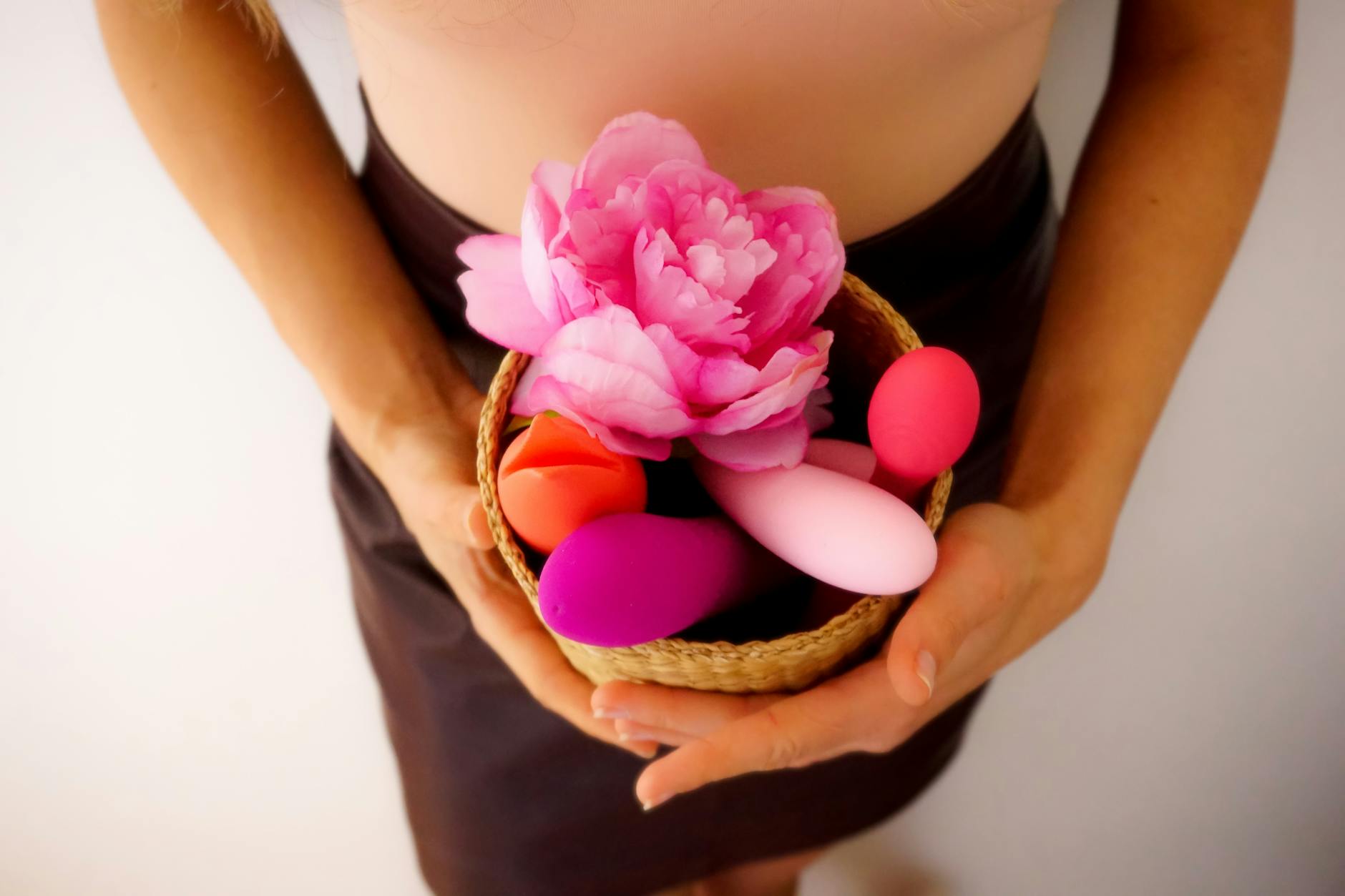 Two hands holding pink and blue silicone vibrators against a soft pastel background, symbolizing the gentle return to pleasure.